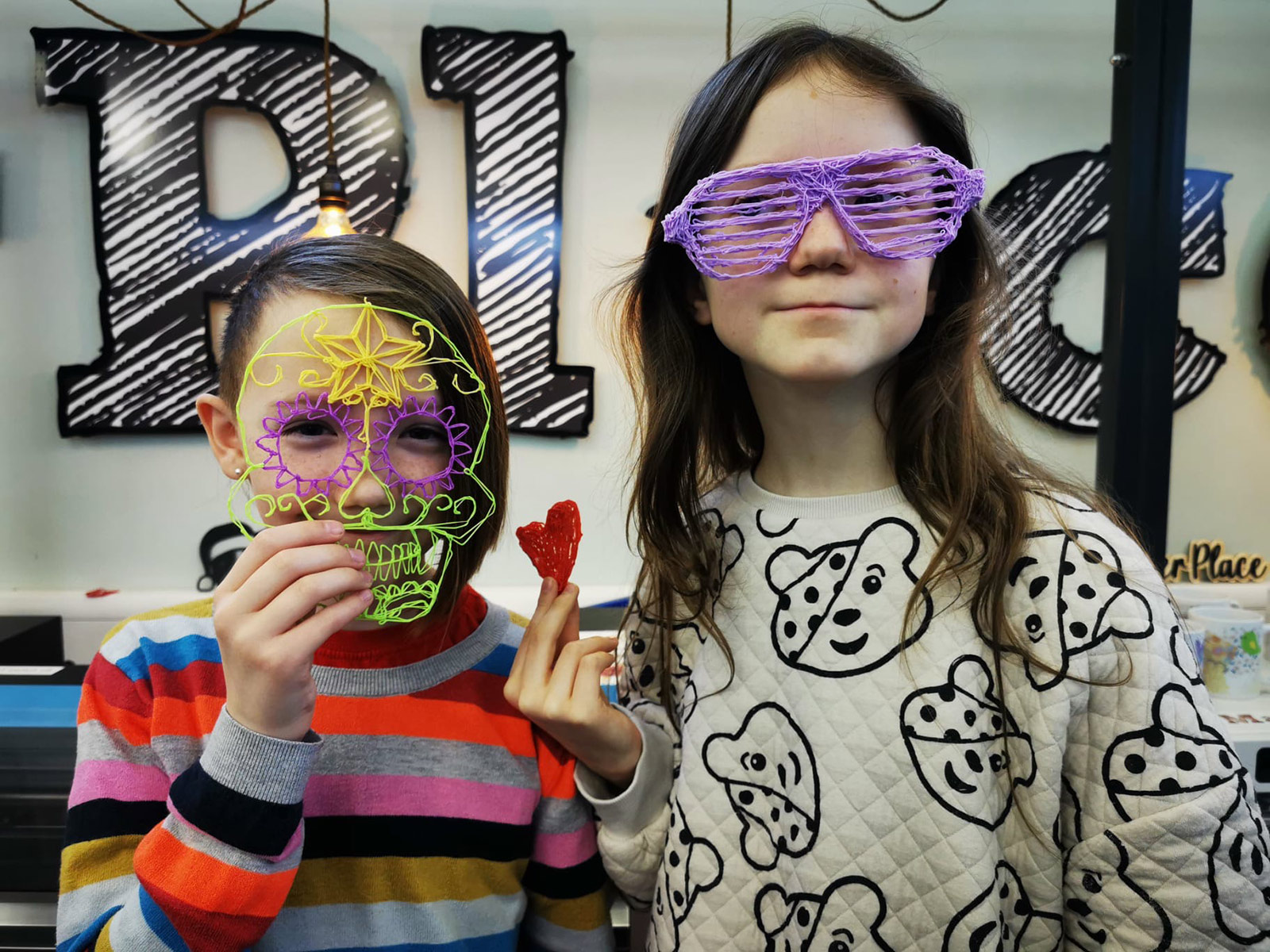 Two children stand with a 3d skull mask and neon purple glasses.