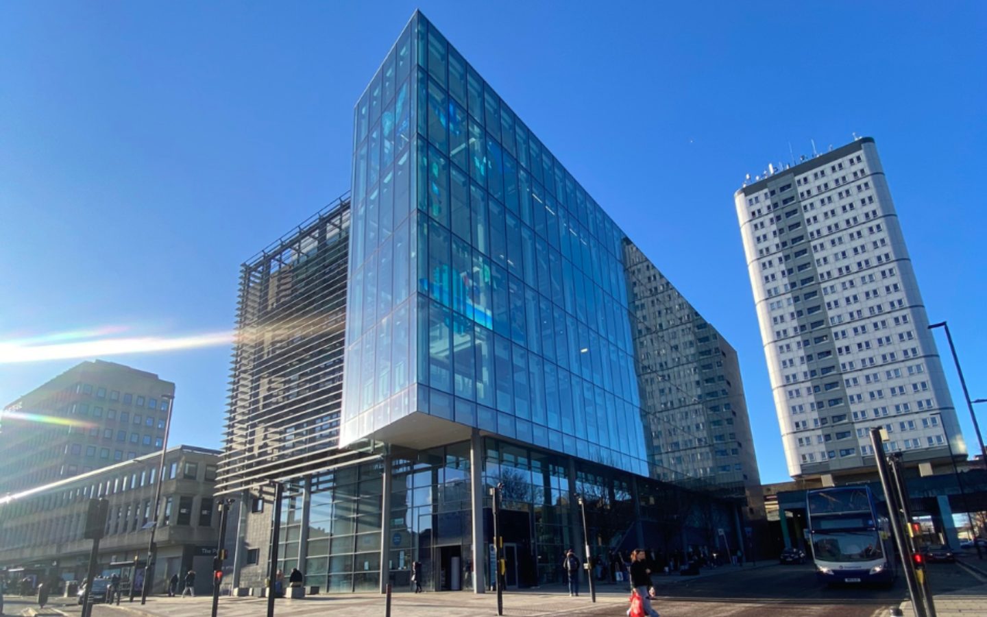 The exterior of a large glass building against a blue sky.