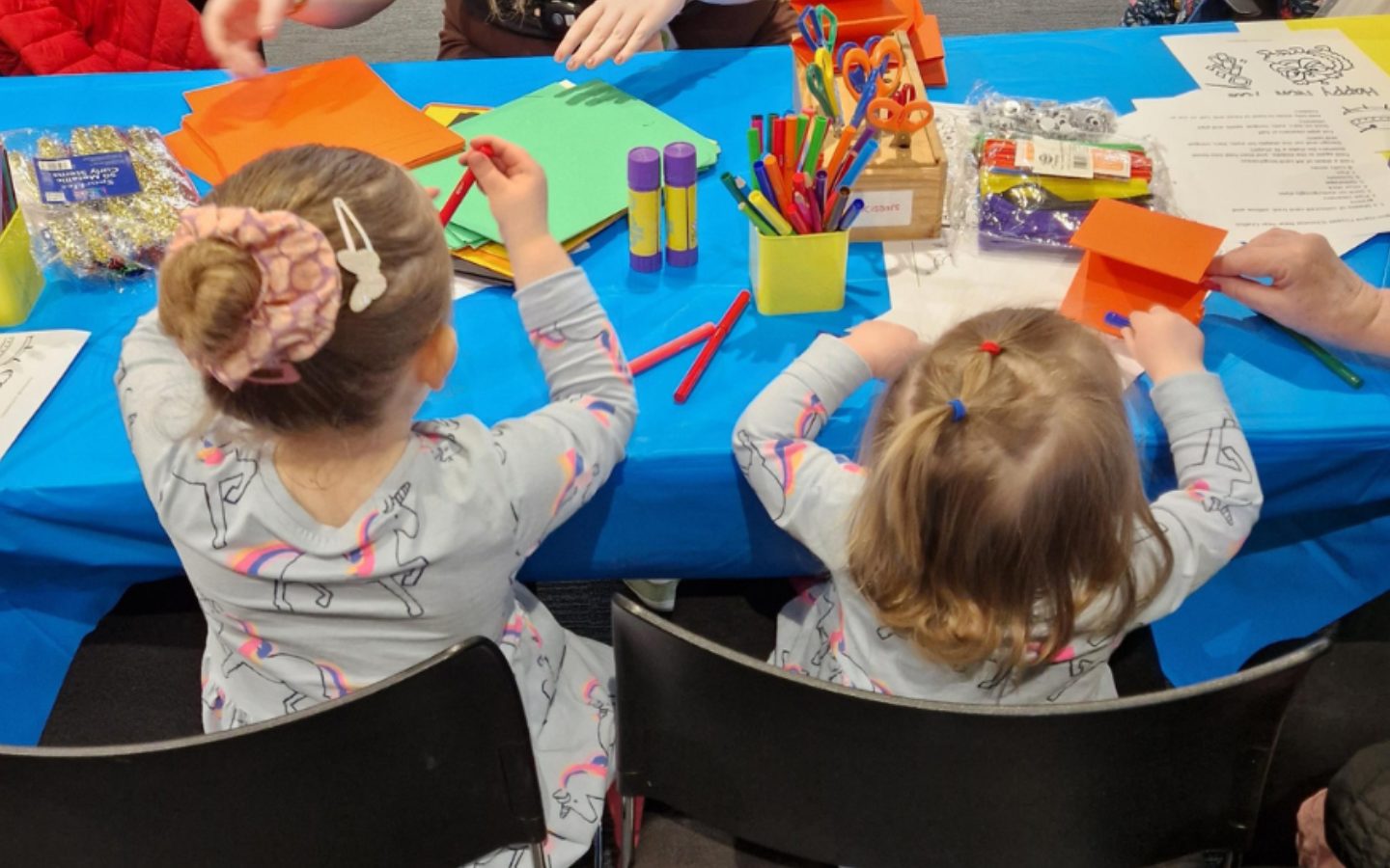 Two children sit at a table abosrbed in crafts.