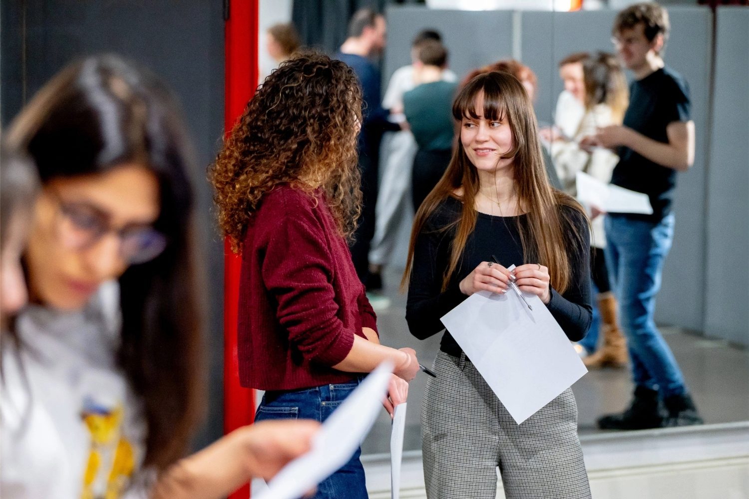 Two teenage girls stand in a drama studio holding scripts.