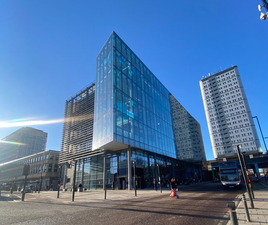 A photo of the exterior of Newcastle City Library against a bright blue sky.