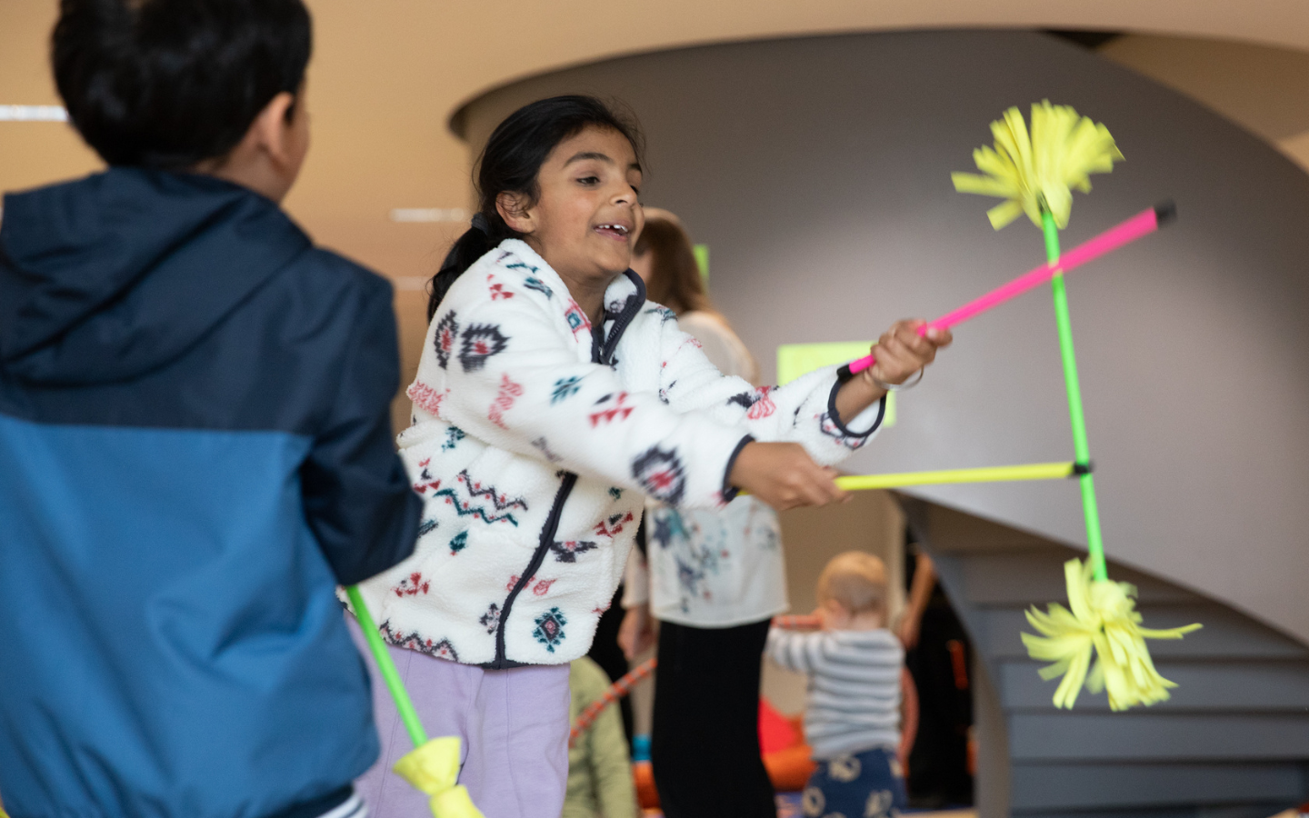 Children play with juggling sticks and batons that are yellow, pink and green.