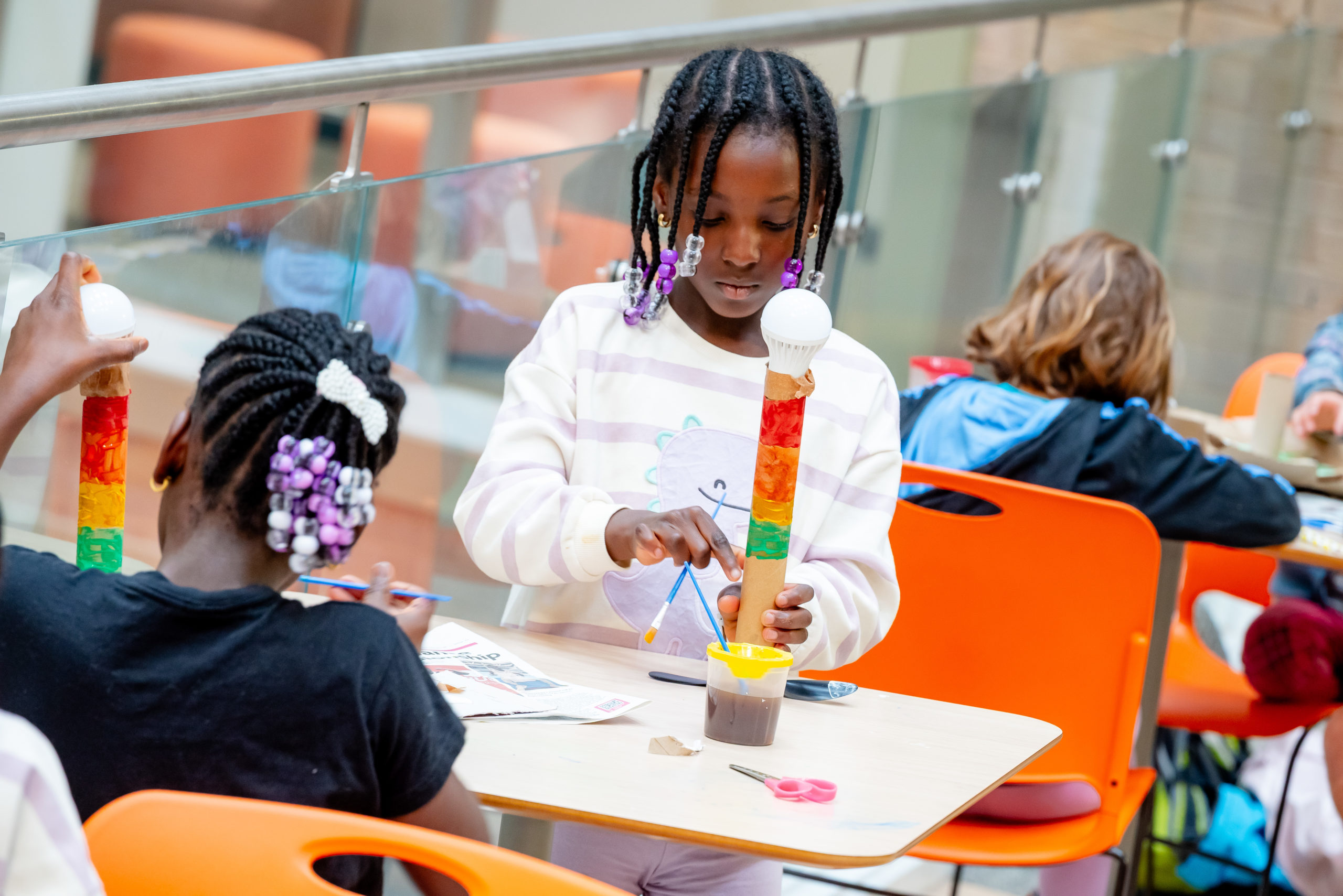 Two children build a brightly coloured tower with craft materials