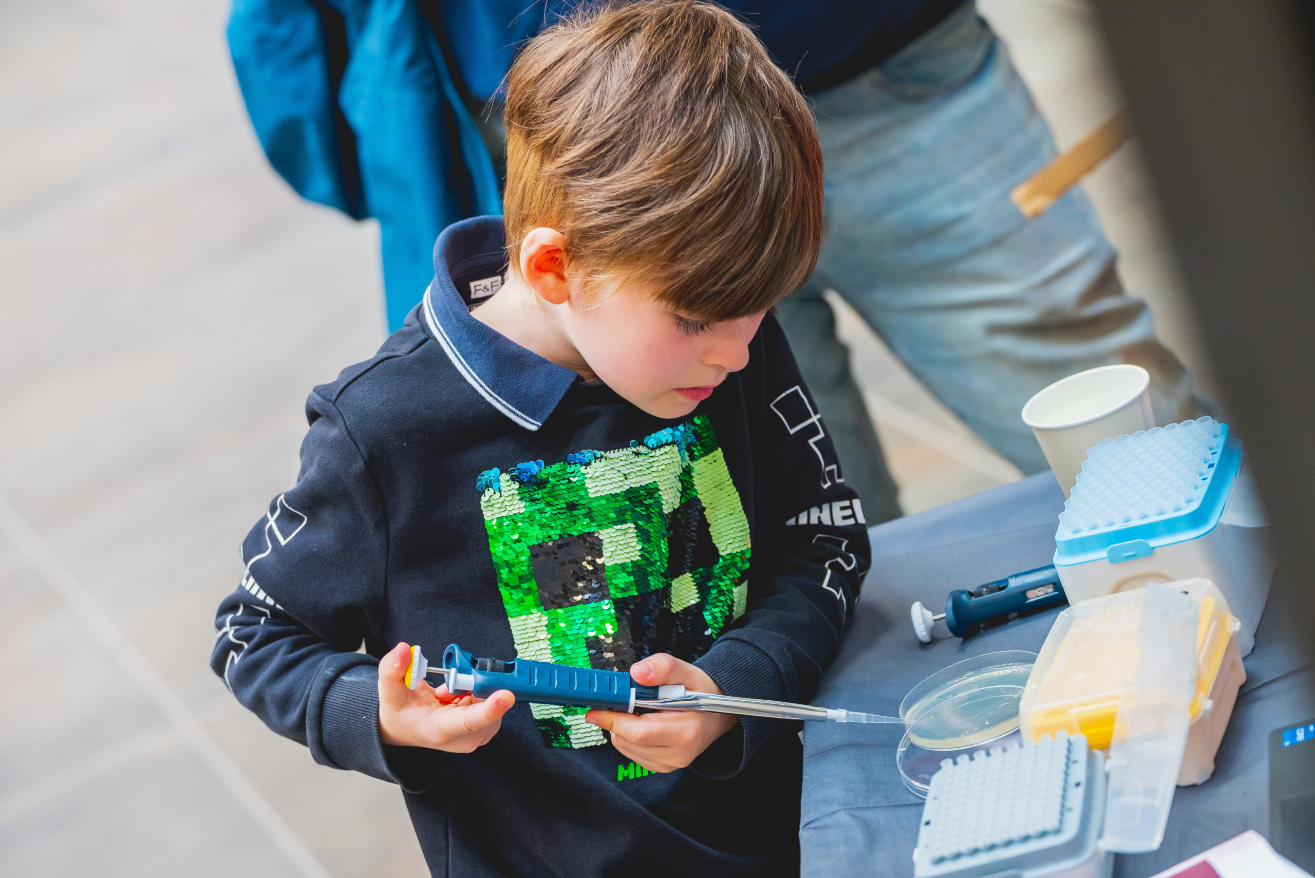 A young child adds a liquid to a preti dish with a pipette