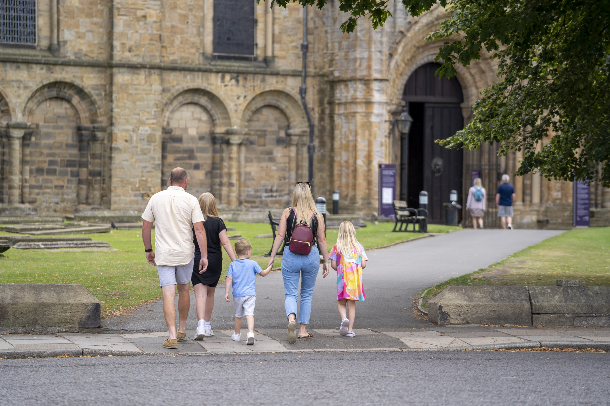 Family external north door approach behind 018 A family walk up to the entrance of Durham Cathedral.