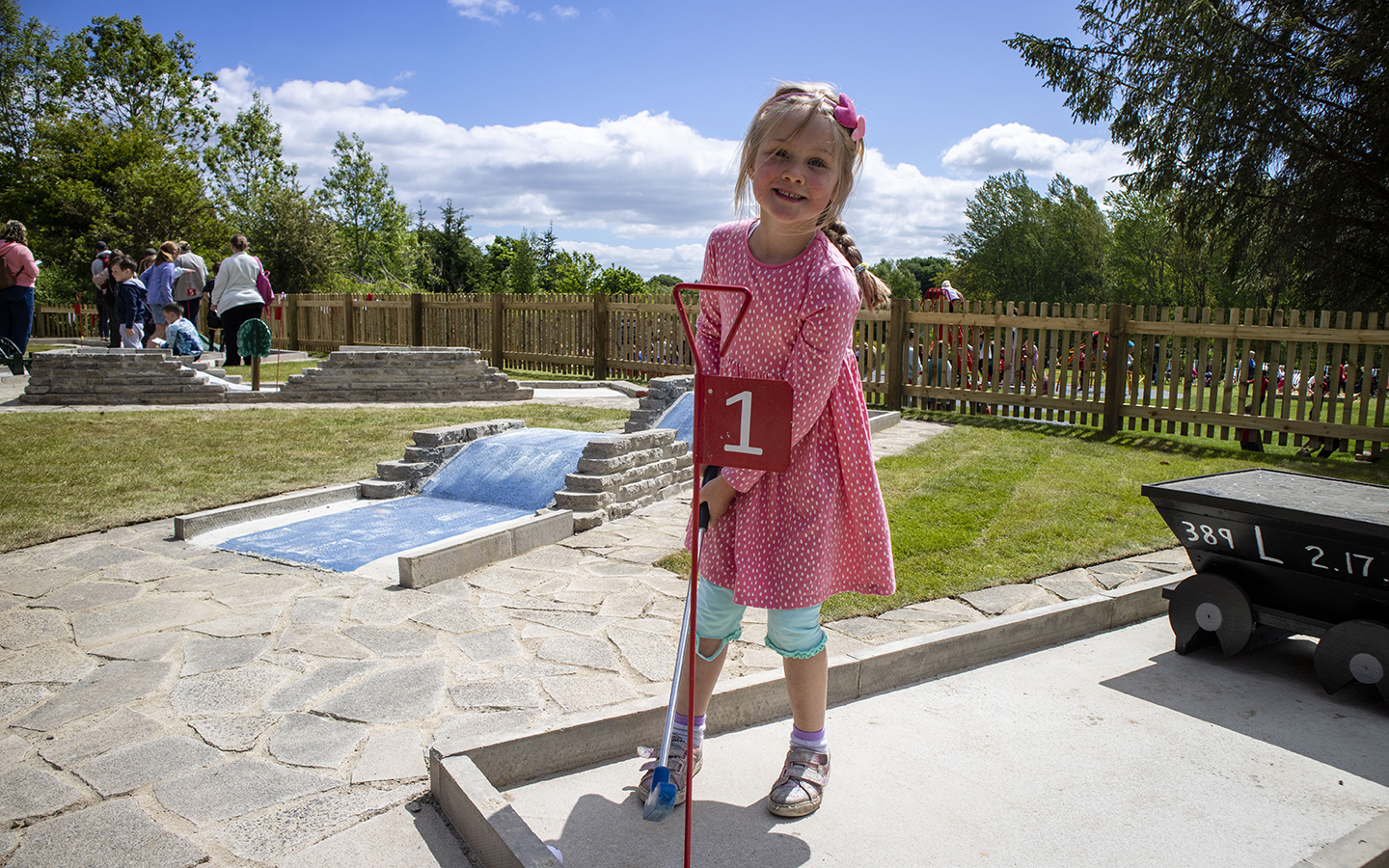 Mini Golf at Beamish Museum A girl wearing a pink polka dot dress, stands at hole number one on a crazy golf course.