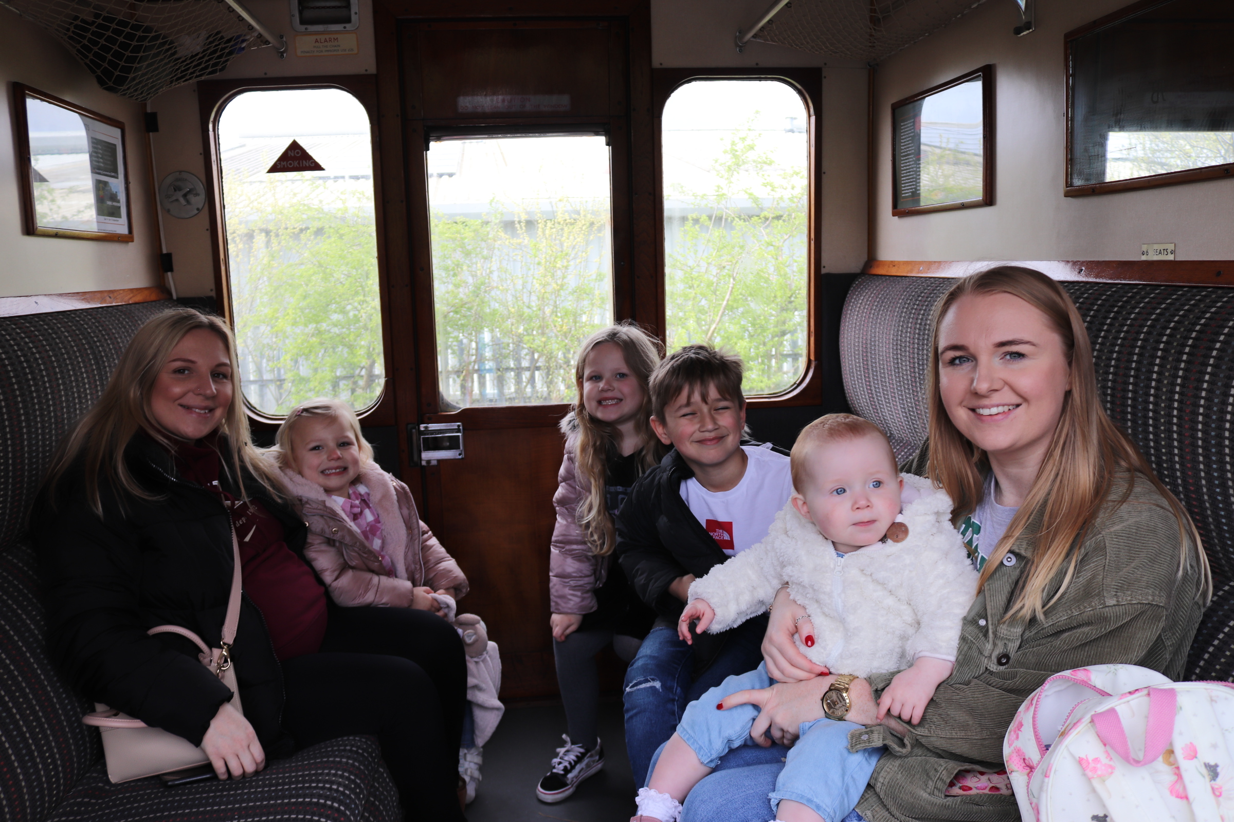 An image of a family group sitting in a train carriage with long seats on either side.