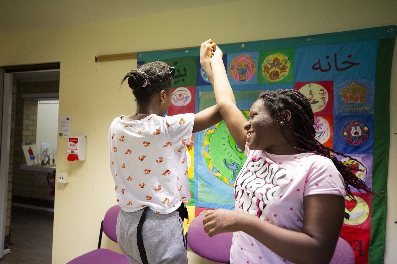 An image of two teenage girls holding hands. One girl is spinning the other.