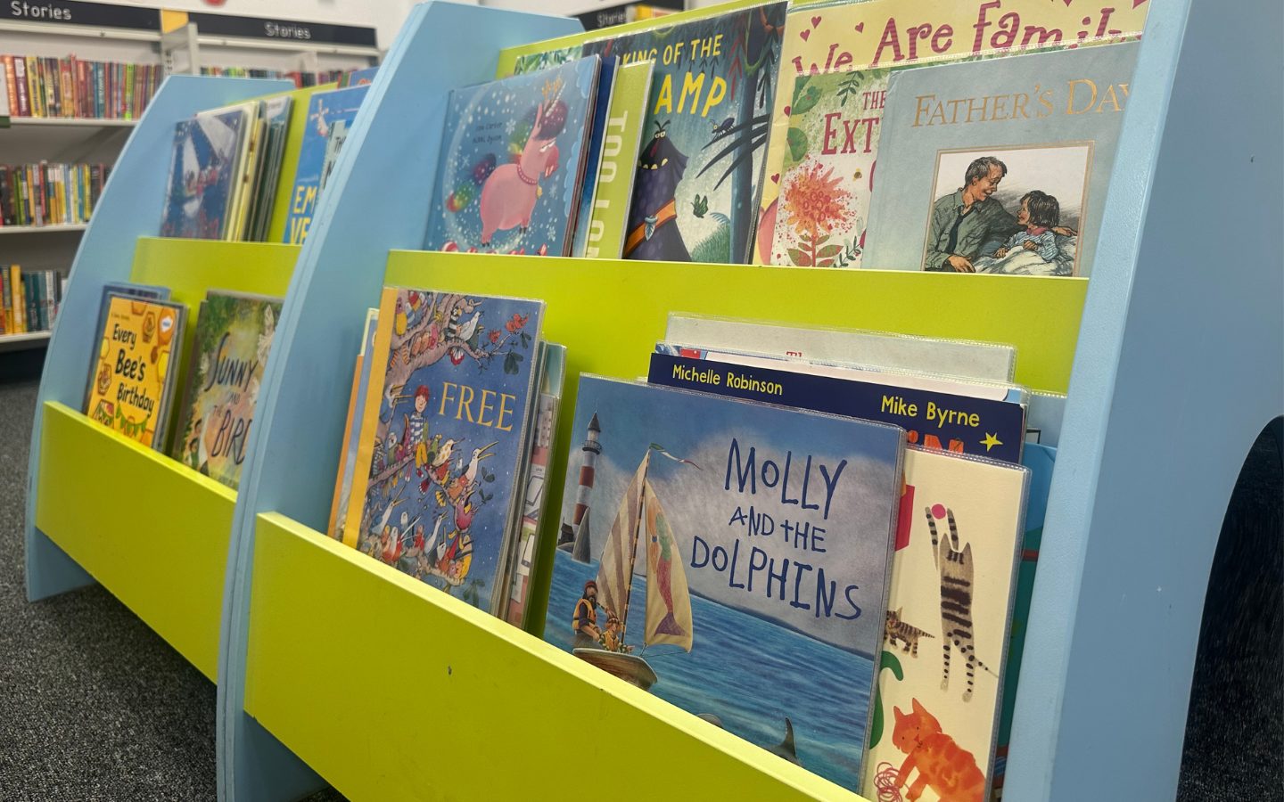 A close up of a brightly coloured bookshelf featuring children's picture books including Molly and the Dolphins.