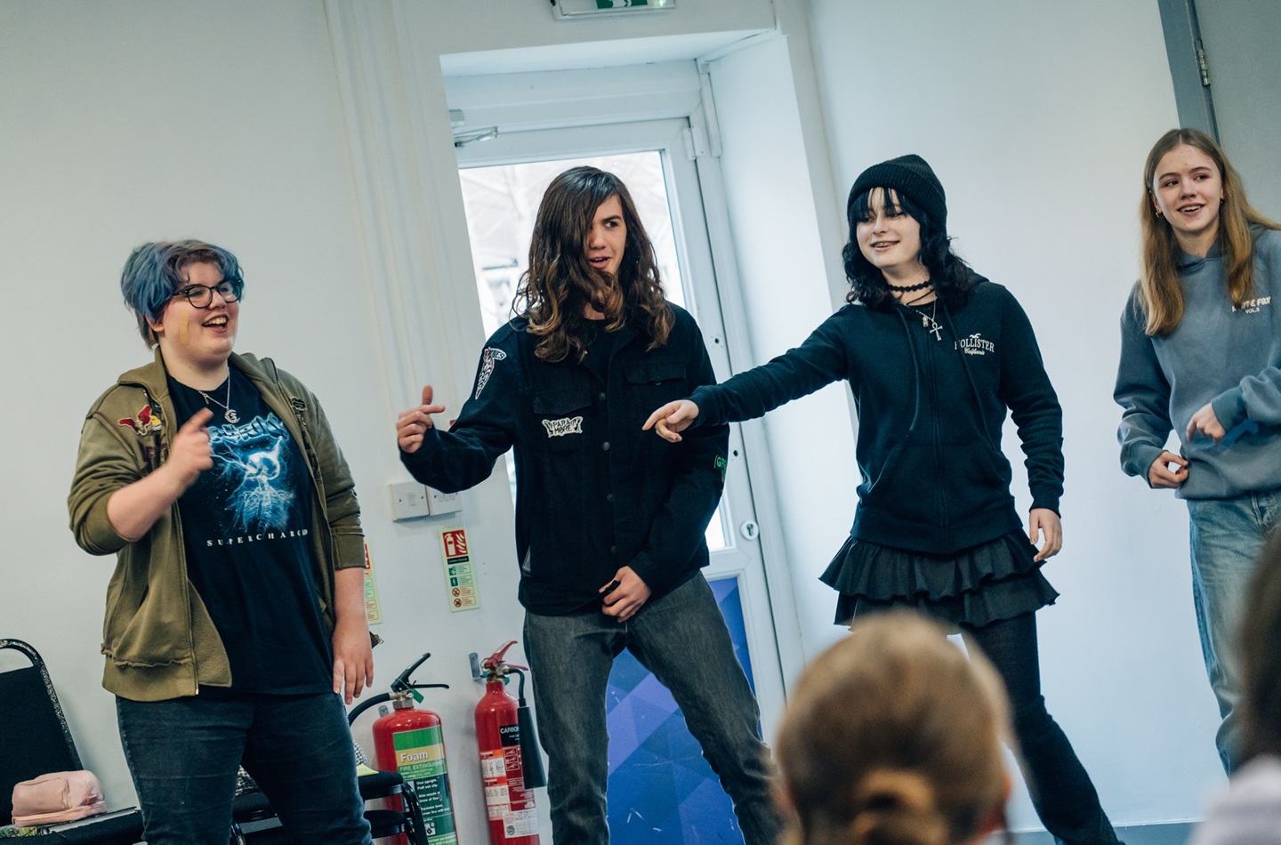 Four young people look animated while giving a performance.