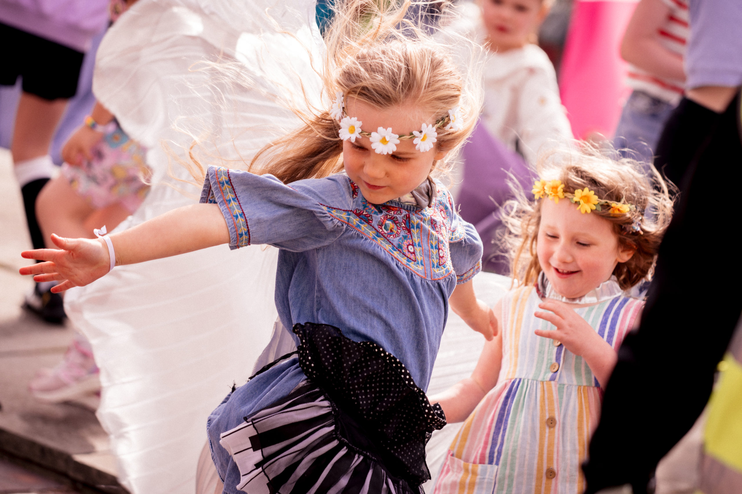 Two children dance wearing daisy crowns.