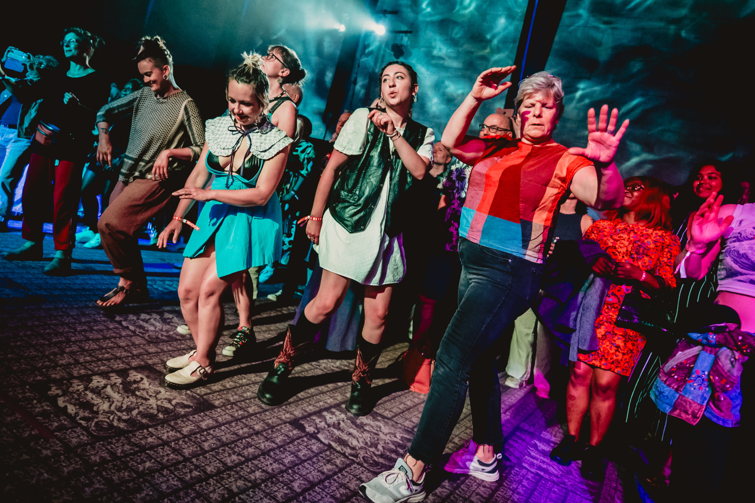 Young people dancing among coloured lights.