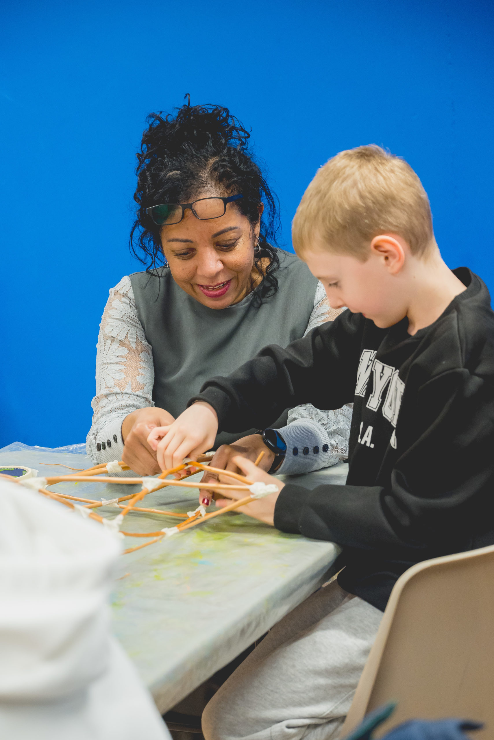An adult and child enthusiastically make a structure out of sticks.
