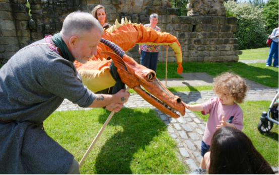 A row of performers hold a giant dragon and a child strokes its nose.