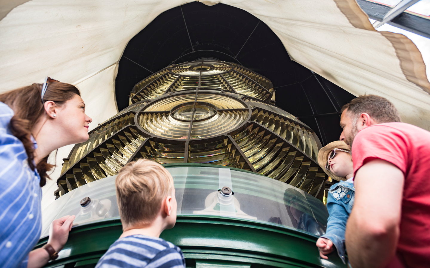 A family looks up at the giant lamps inside a lighthouse.