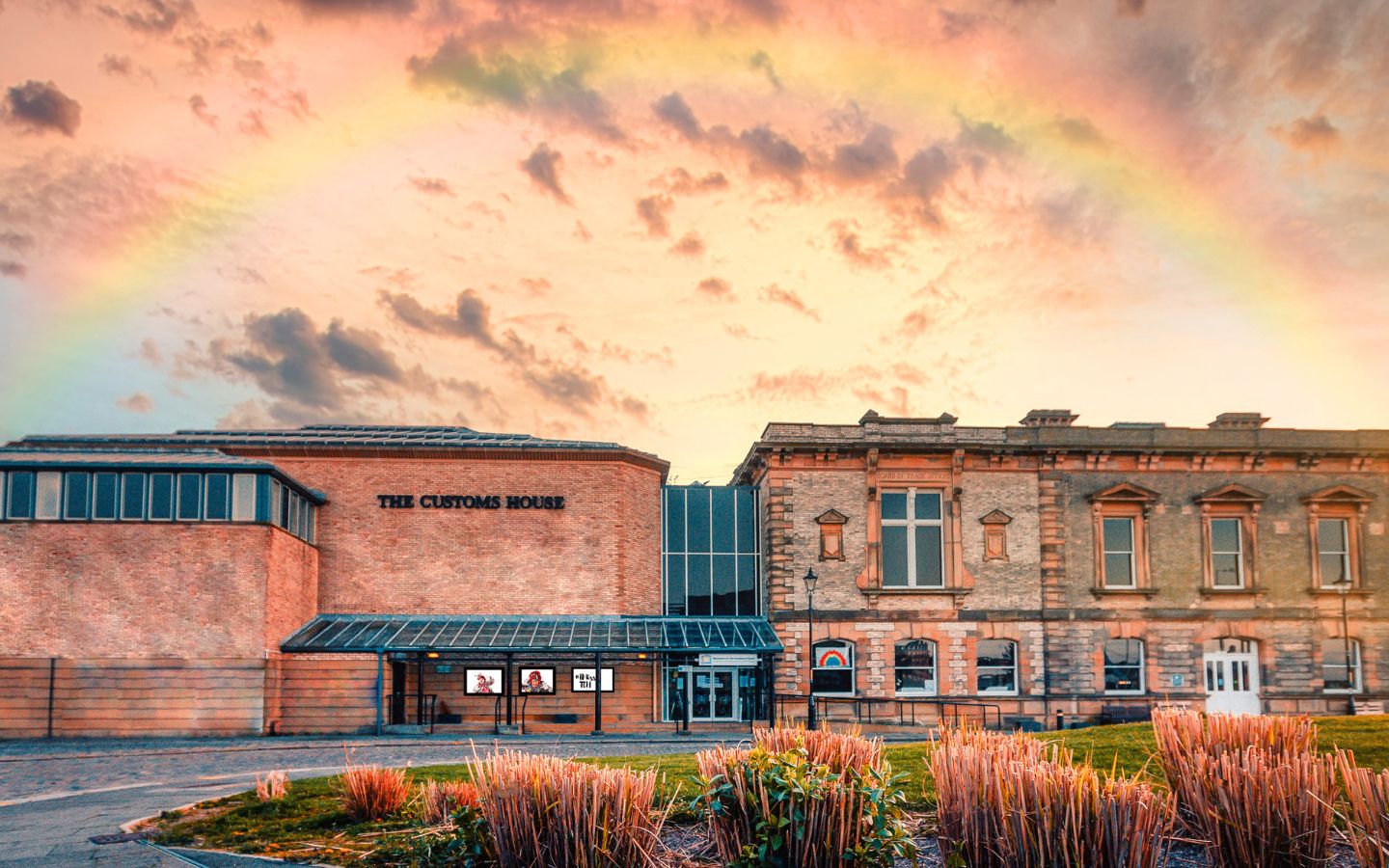 The exterior of a large character red brick building with the words 'Customs House' on it.